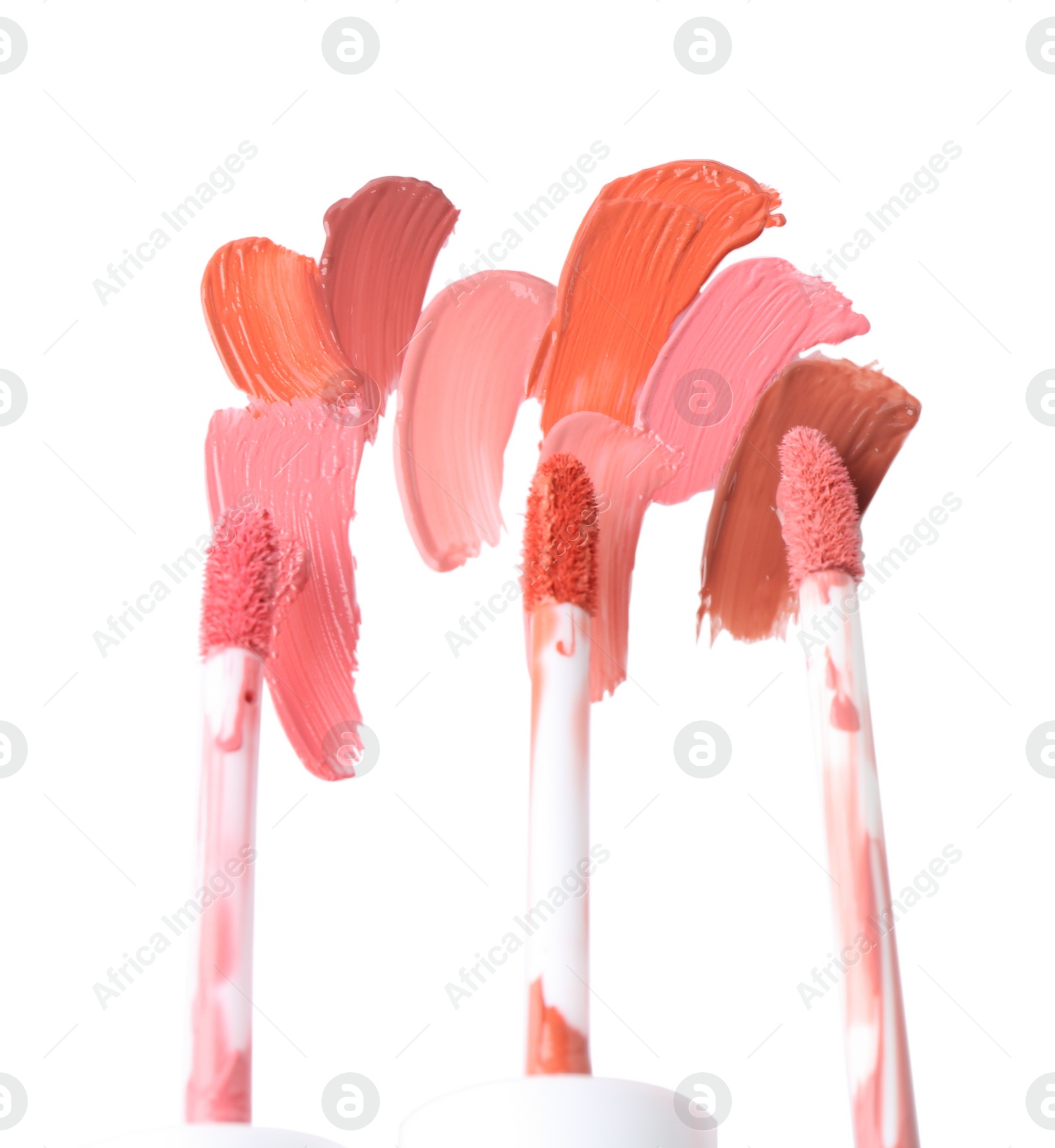 Photo of Strokes of different lip glosses and applicators isolated on white, top view