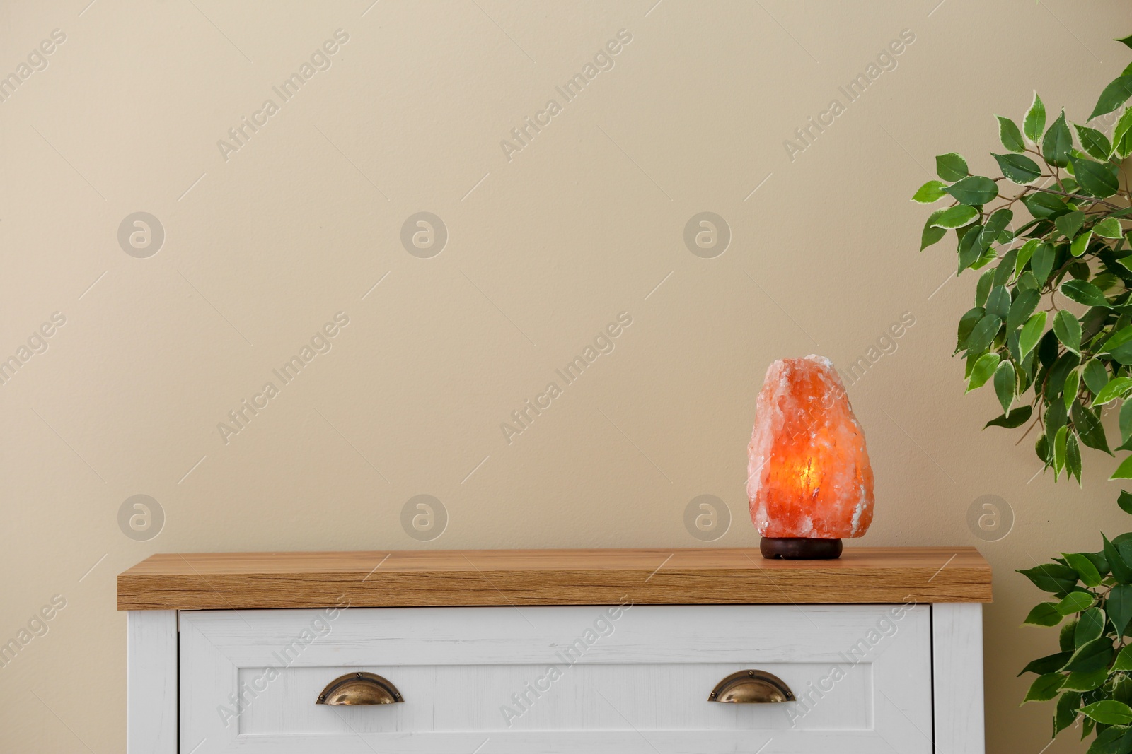 Photo of Himalayan salt lamp on cabinet against light wall