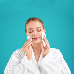 Photo of Beautiful young woman with cotton pads on turquoise background