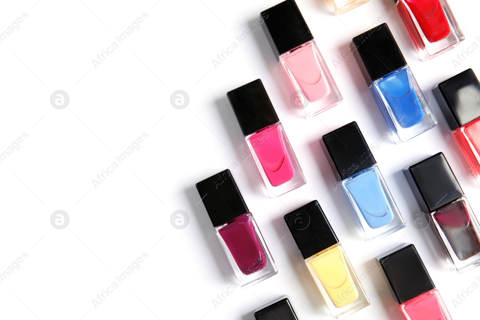 Photo of Bottles of bright nail polish on white background, top view