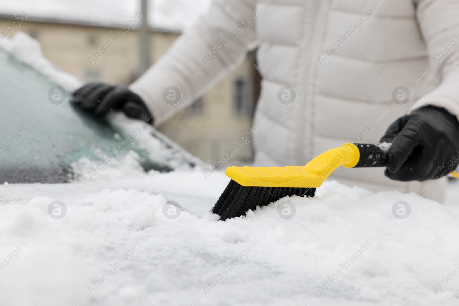 Photo of Man cleaning snow from car hood outdoors, closeup