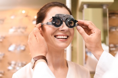 Photo of Woman having eye examination with phoropter in optical store. Ophthalmologist prescription