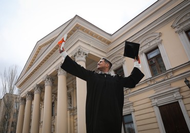 Photo of Happy student with diploma after graduation ceremony outdoors, low angle view