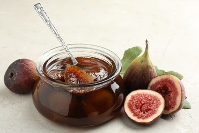 Jar of tasty sweet jam and fresh figs on white table