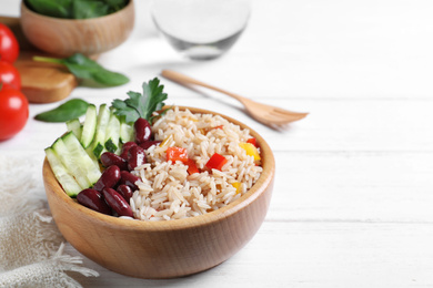 Photo of Delicious rice with beans served on white wooden table