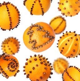 Image of Different pomander balls made of fresh tangerines and cloves falling on white background