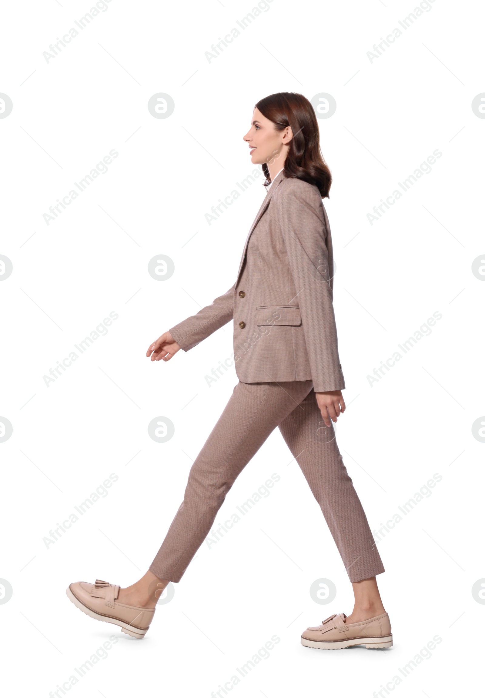 Photo of Beautiful young woman in formal suit walking on white background