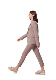 Beautiful young woman in formal suit walking on white background