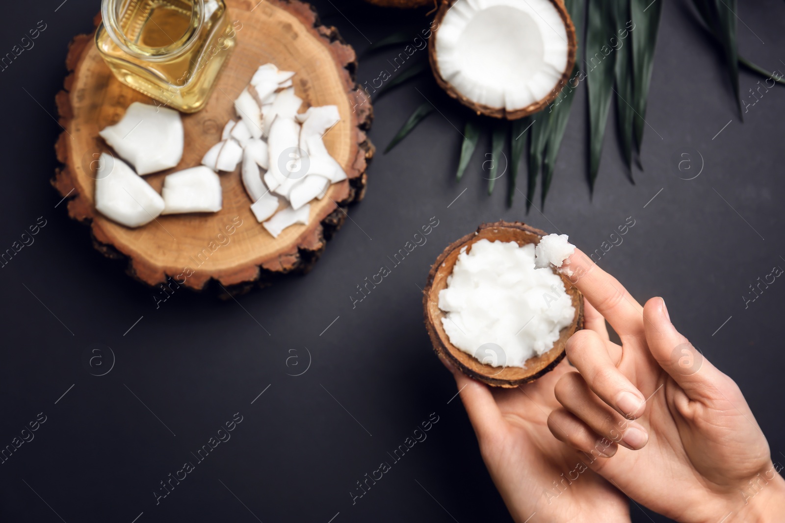 Photo of Young woman with coconut oil on grey background, closeup