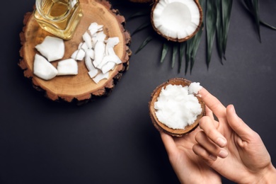 Photo of Young woman with coconut oil on grey background, closeup