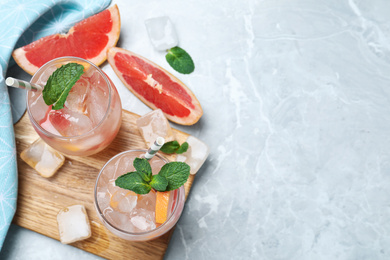 Photo of Glasses of fresh cocktail with grapefruit on light grey marble table, flat lay. Space for text