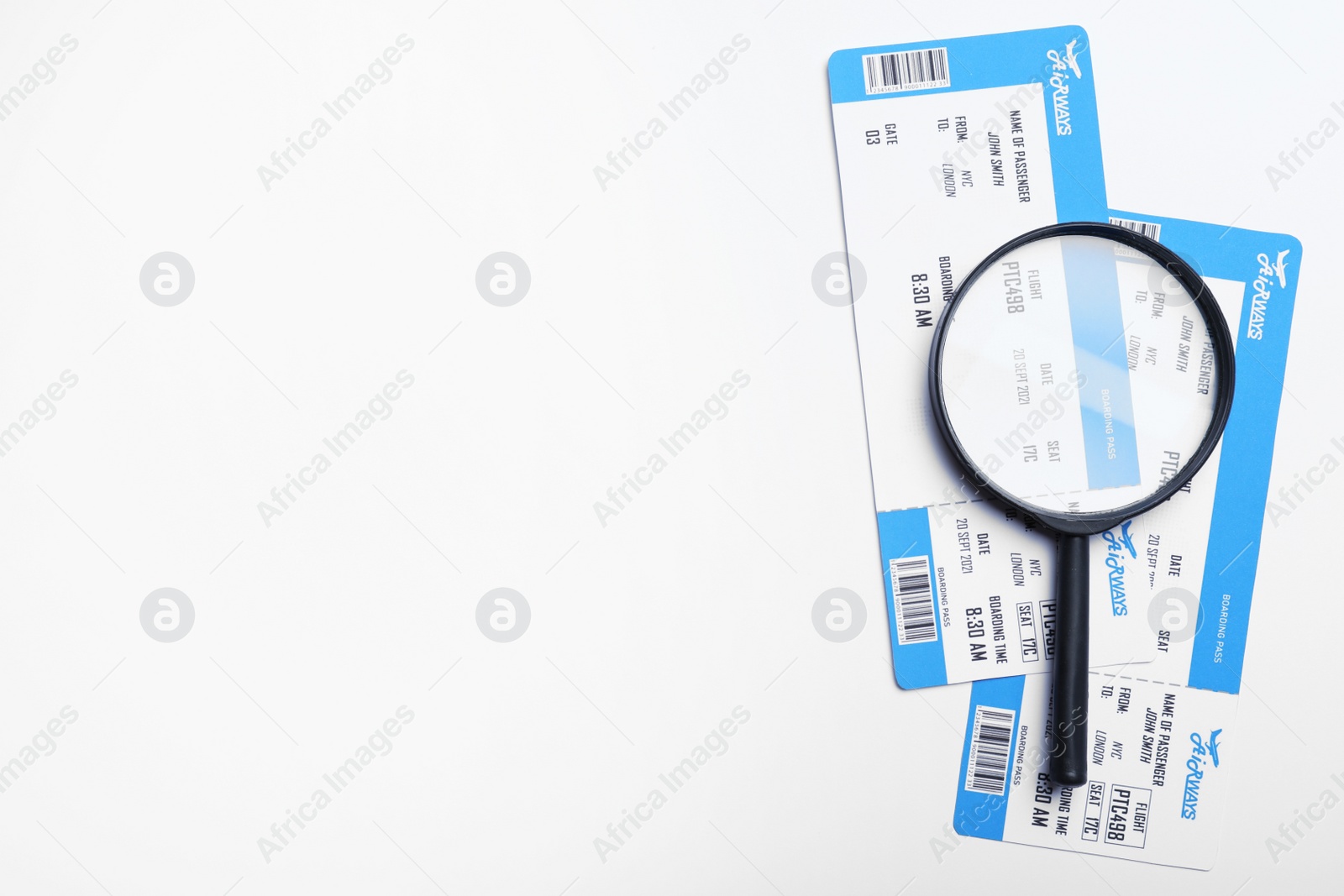 Photo of Avia tickets and magnifying glass on white background, flat lay with space for text. Travel agency concept