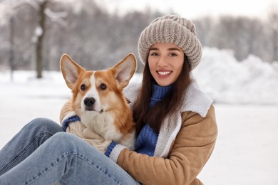 Photo of Woman with adorable Pembroke Welsh Corgi dog in snowy park