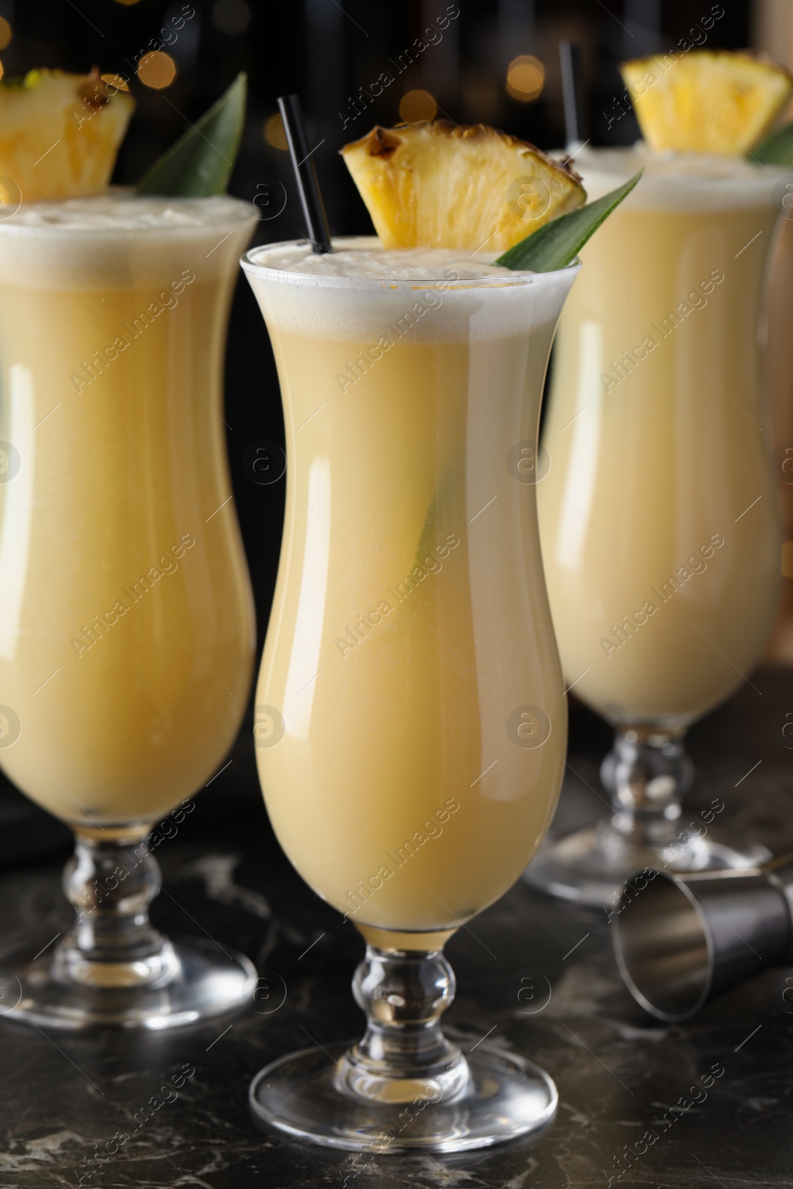 Photo of Tasty Pina Colada cocktails on black marble bar countertop