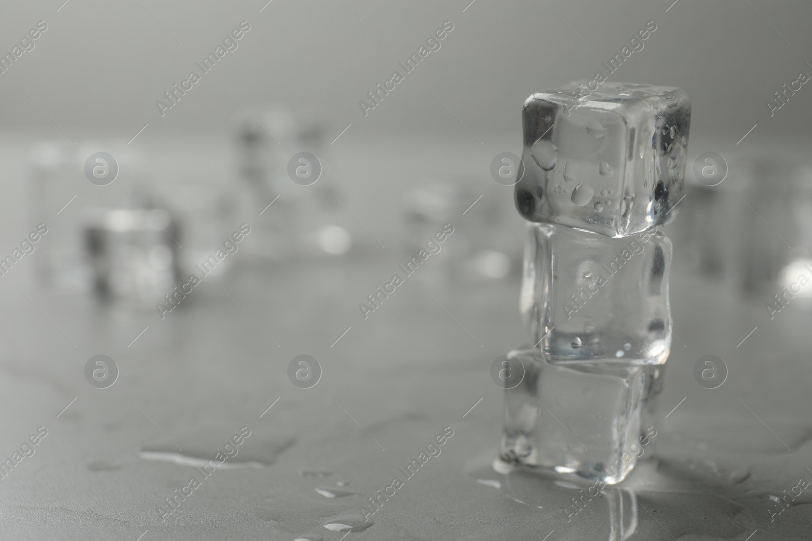 Photo of Crystal clear ice cubes with water drops on grey table, closeup. Space for text