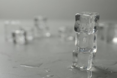 Crystal clear ice cubes with water drops on grey table, closeup. Space for text