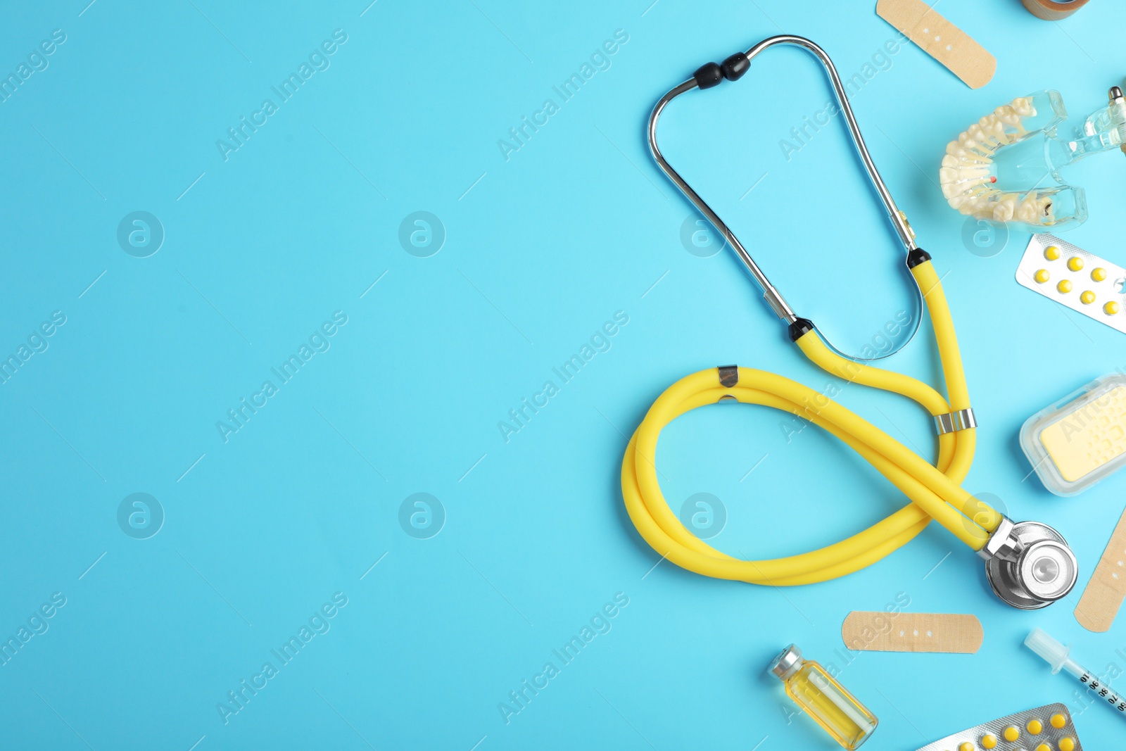 Photo of Flat lay composition with stethoscope and pills on color background, space for text. Medical tools