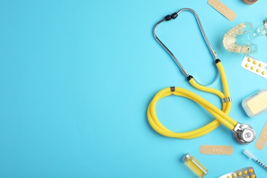 Photo of Flat lay composition with stethoscope and pills on color background, space for text. Medical tools