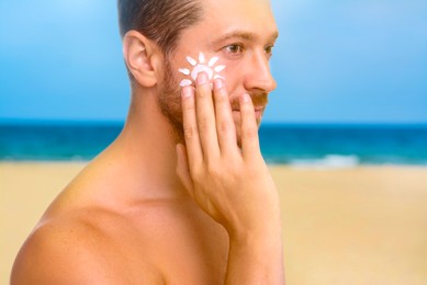 Image of Sun protection. Man applying sunblock onto face on beach, closeup
