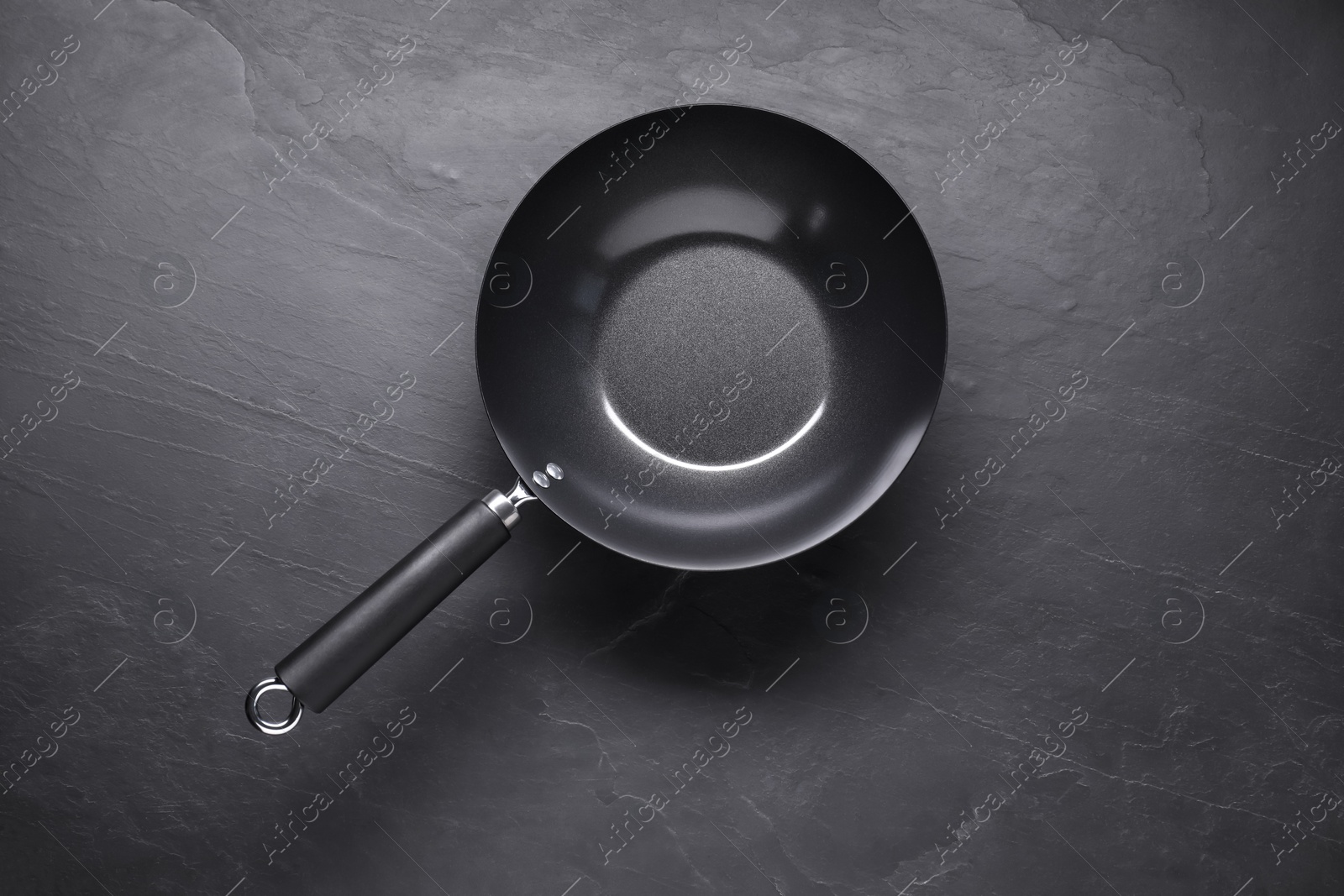 Photo of Empty iron wok on black textured table, top view. Chinese cookware