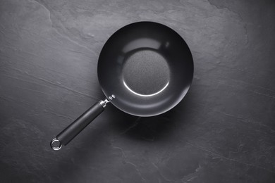 Empty iron wok on black textured table, top view. Chinese cookware