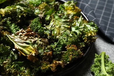 Photo of Tasty baked kale chips on table, closeup