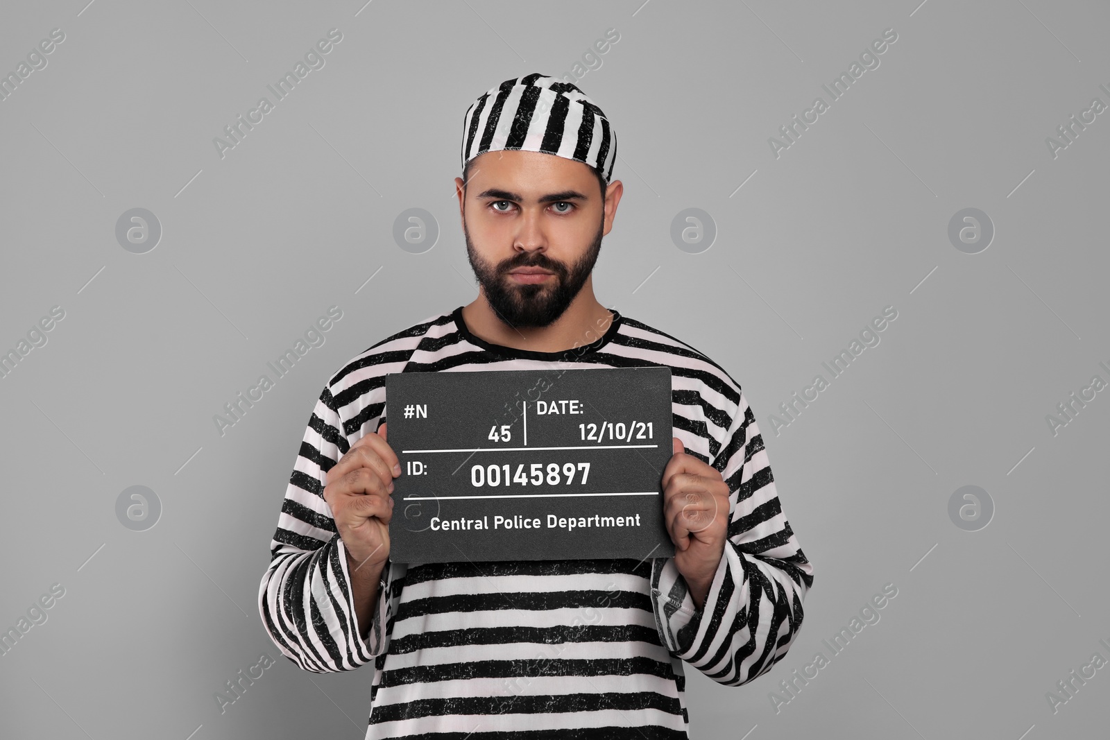 Photo of Prisoner in special uniform with mugshot letter board  
on grey background