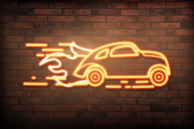 Glowing neon sign with driving car and flames on brick wall