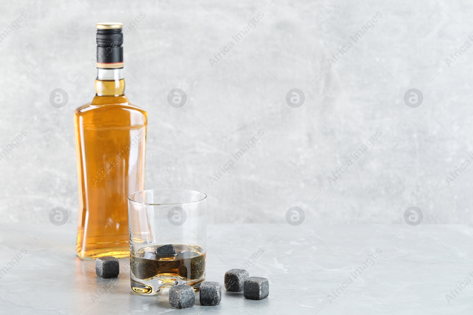 Photo of Whiskey stones and drink on light marble table. Space for text