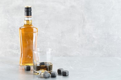 Whiskey stones and drink on light marble table. Space for text