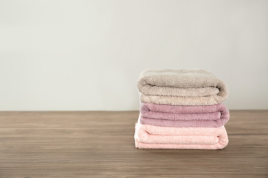 Photo of Stack of color towels on wooden table. Space for text