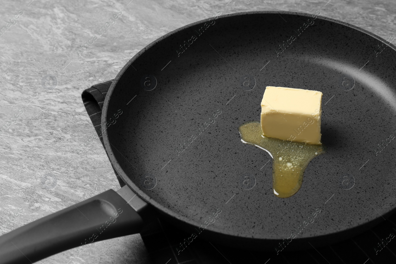 Photo of Frying pan with melting butter on grey table, closeup