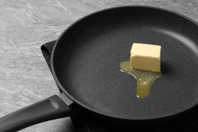 Frying pan with melting butter on grey table, closeup