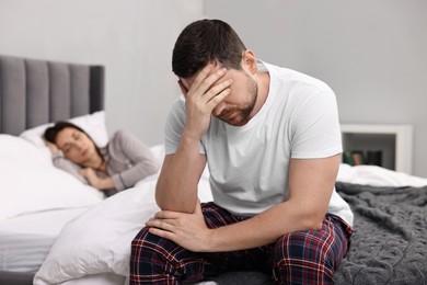 Stressed husband after quarrel with his wife in bedroom, selective focus. Relationship problems