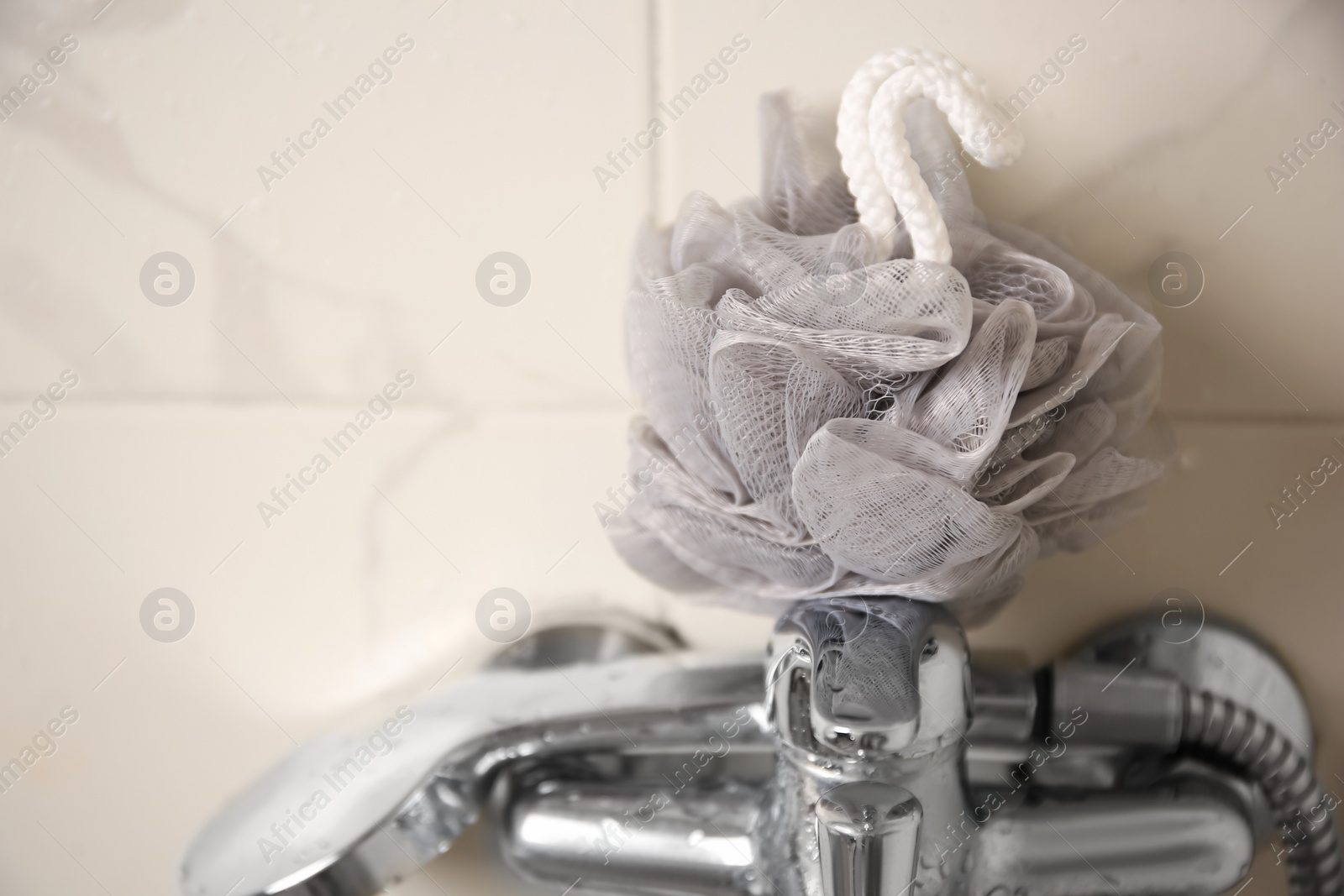 Photo of Grey shower puff on faucet in bathroom, closeup