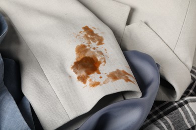 Photo of Shirts and dirty jacket with stain of coffee as background, closeup