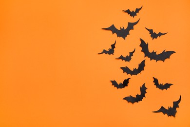 Photo of Paper bats and space for text on orange background, flat lay. Halloween decor