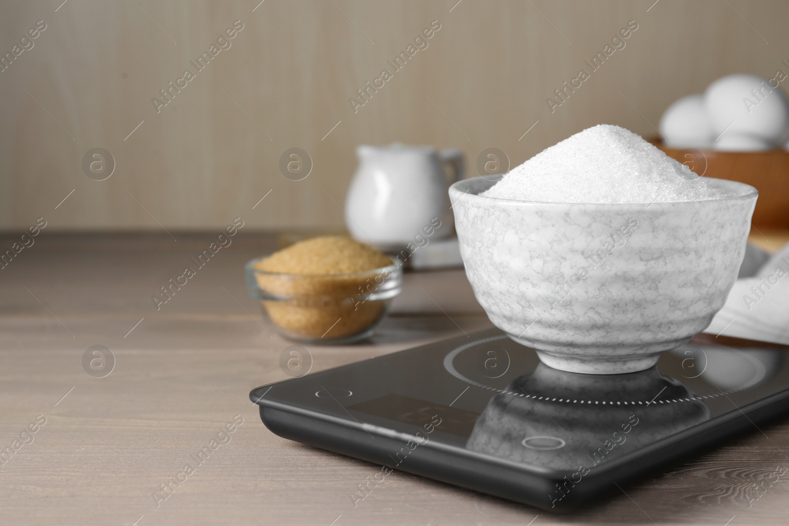 Photo of Electronic scales with sugar on light wooden table, space for text