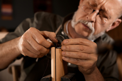 Man sewing piece of leather in workshop, closeup