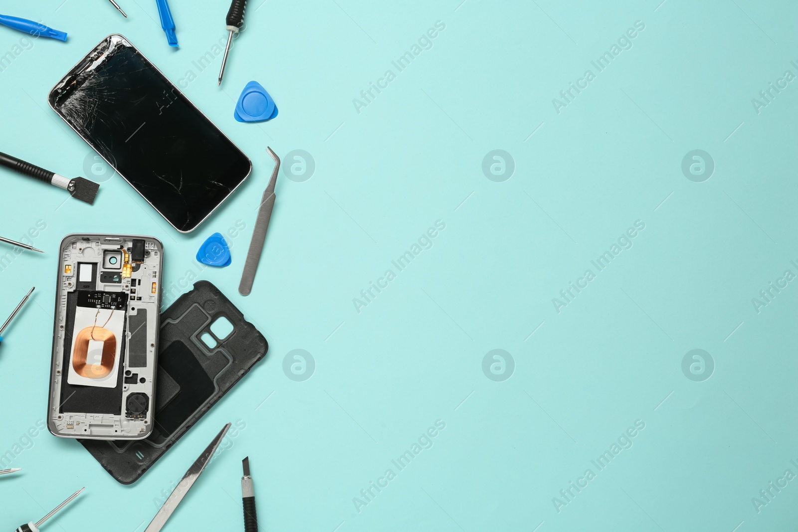 Photo of Damaged smartphone and repair tool set on light blue background, flat lay. Space for text