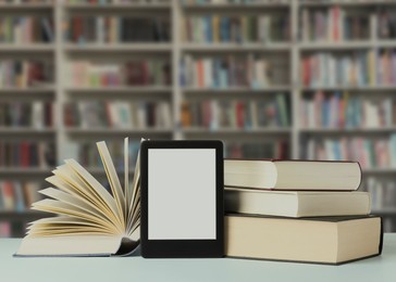 Image of Hardcover books and modern e-book on table in library