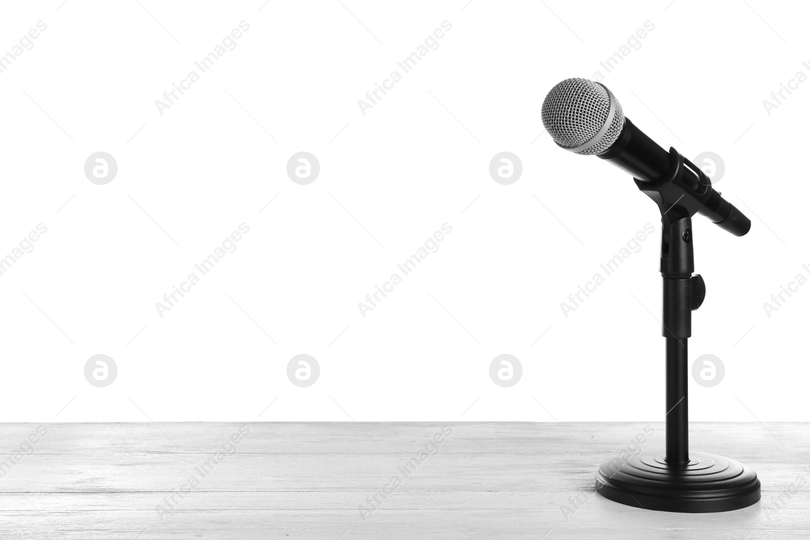 Photo of Modern microphone on table against white background. Space for text