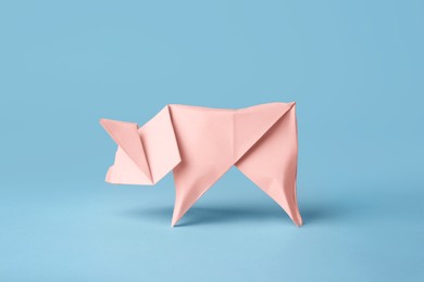 Origami art. Handmade pink paper pig on light blue background