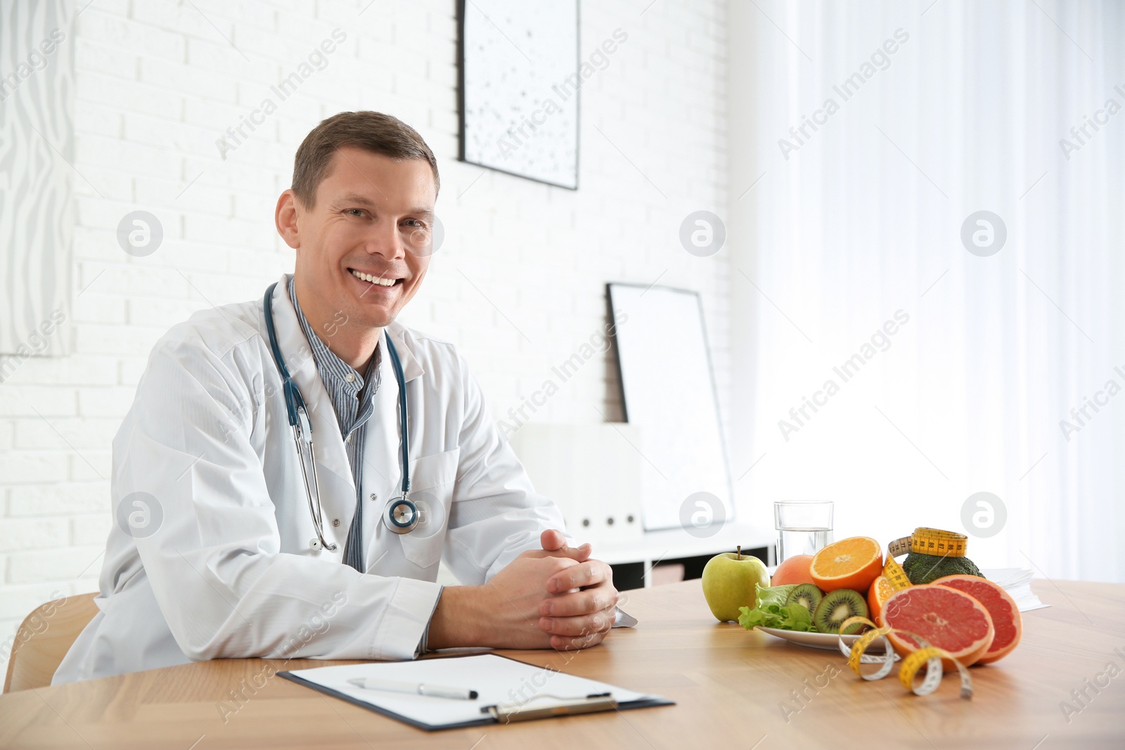 Photo of Nutritionist with clipboard at desk in office