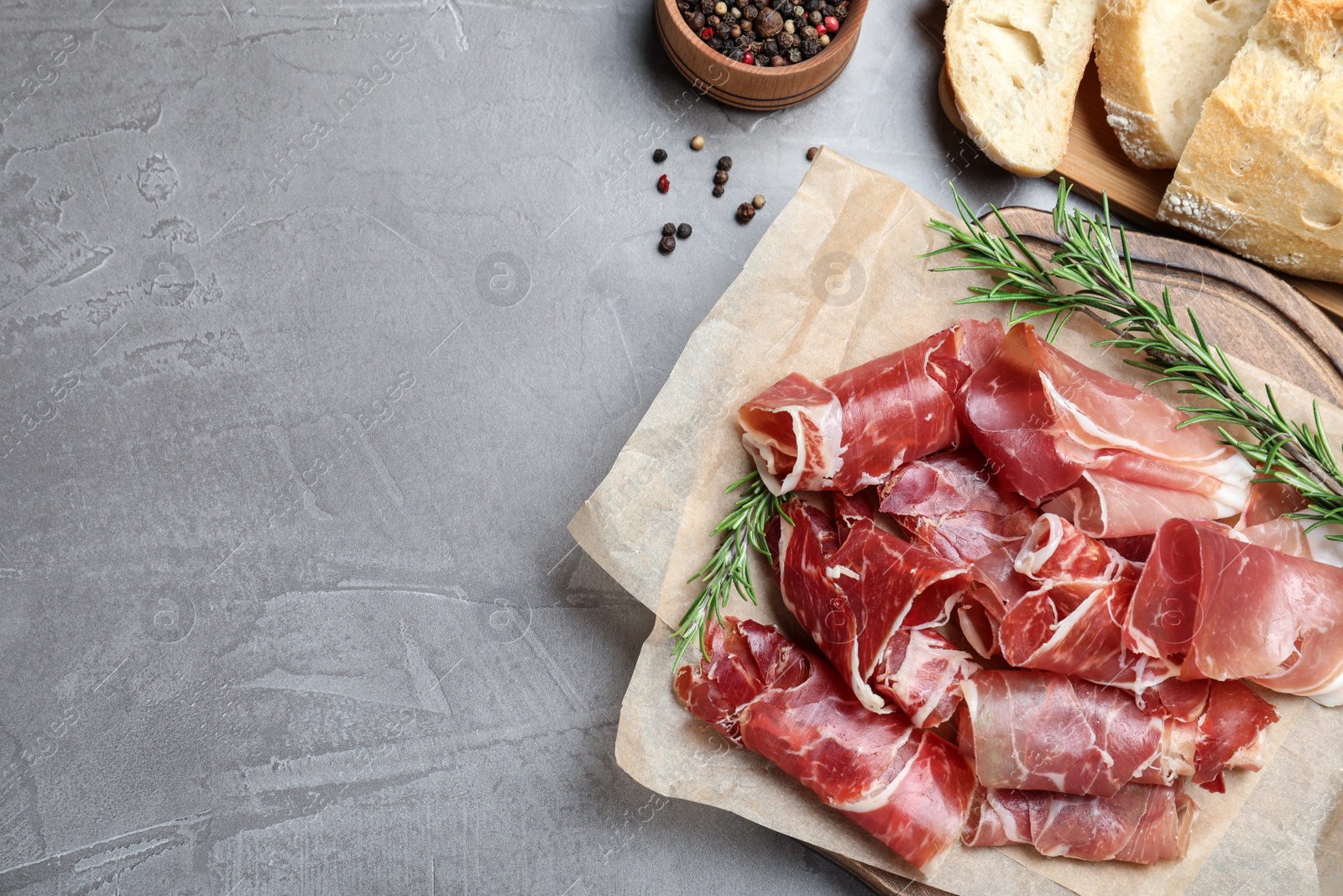 Photo of Tasty prosciutto on grey table, flat lay. Space for text