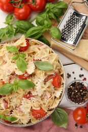 Photo of Plate of delicious pasta with tomatoes, basil and parmesan cheese near ingredients on white wooden table, flat lay