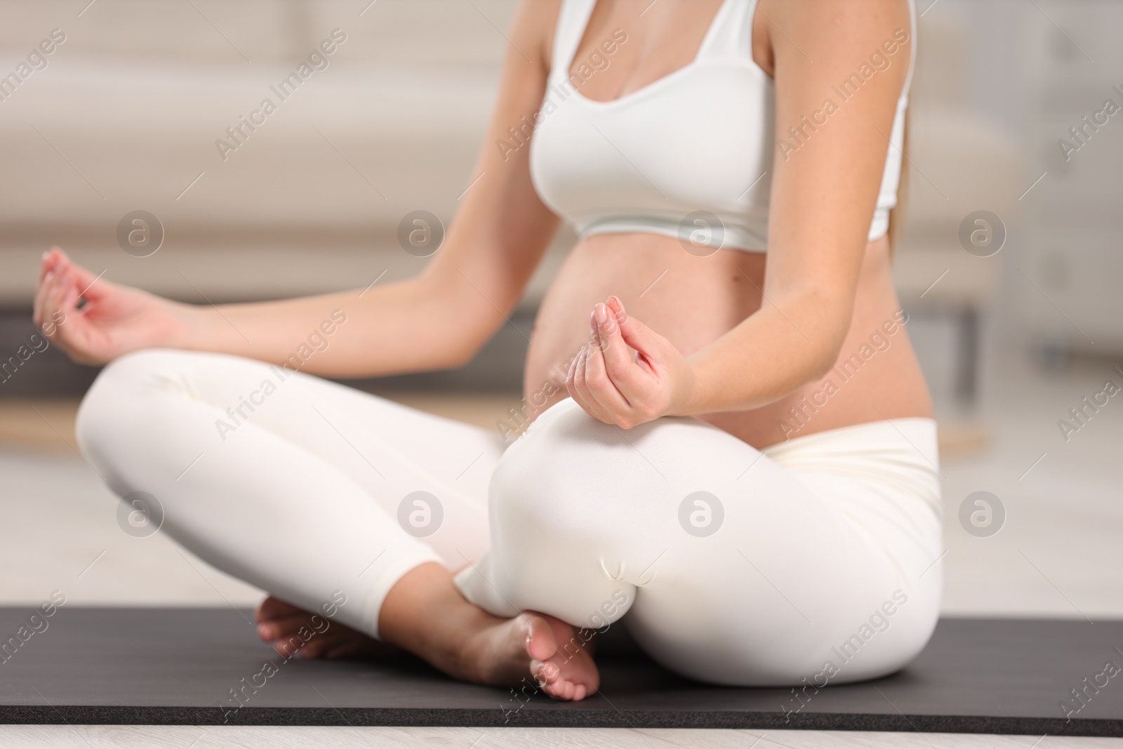 Photo of Pregnant woman meditating on yoga mat at home, closeup