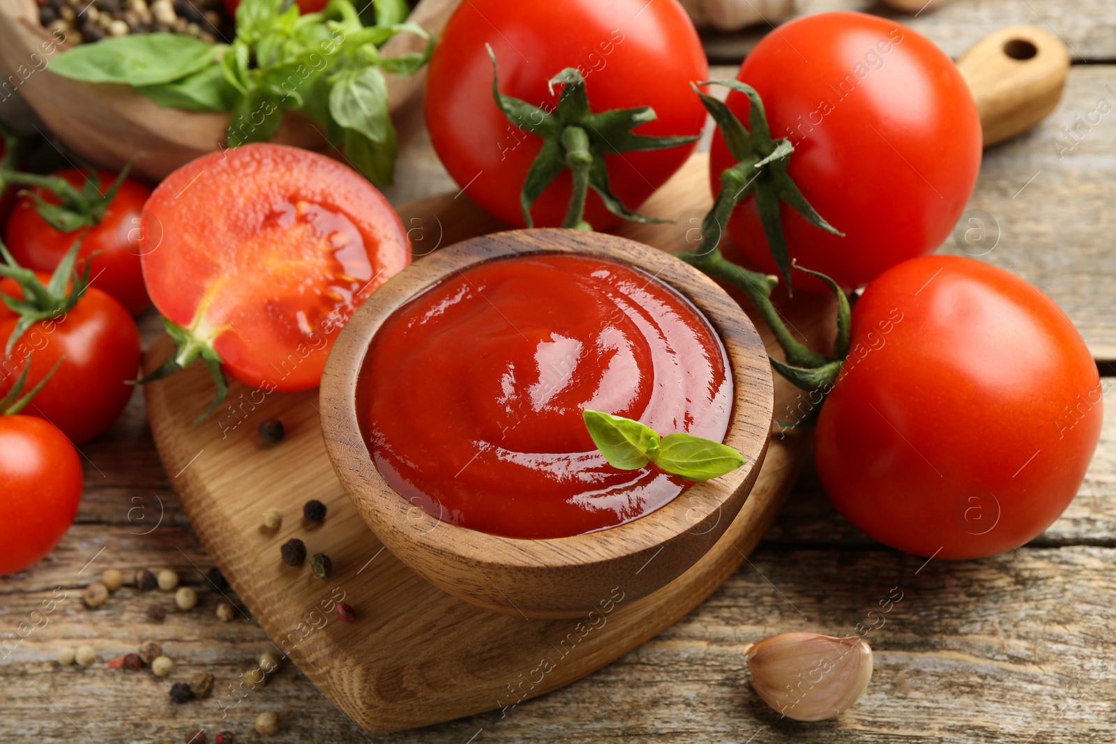 Photo of Tasty ketchup, fresh tomatoes, basil and spices on wooden table