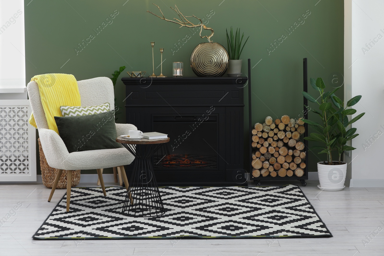 Photo of Stylish living room with beautiful fireplace, armchair, table and houseplants. Interior design