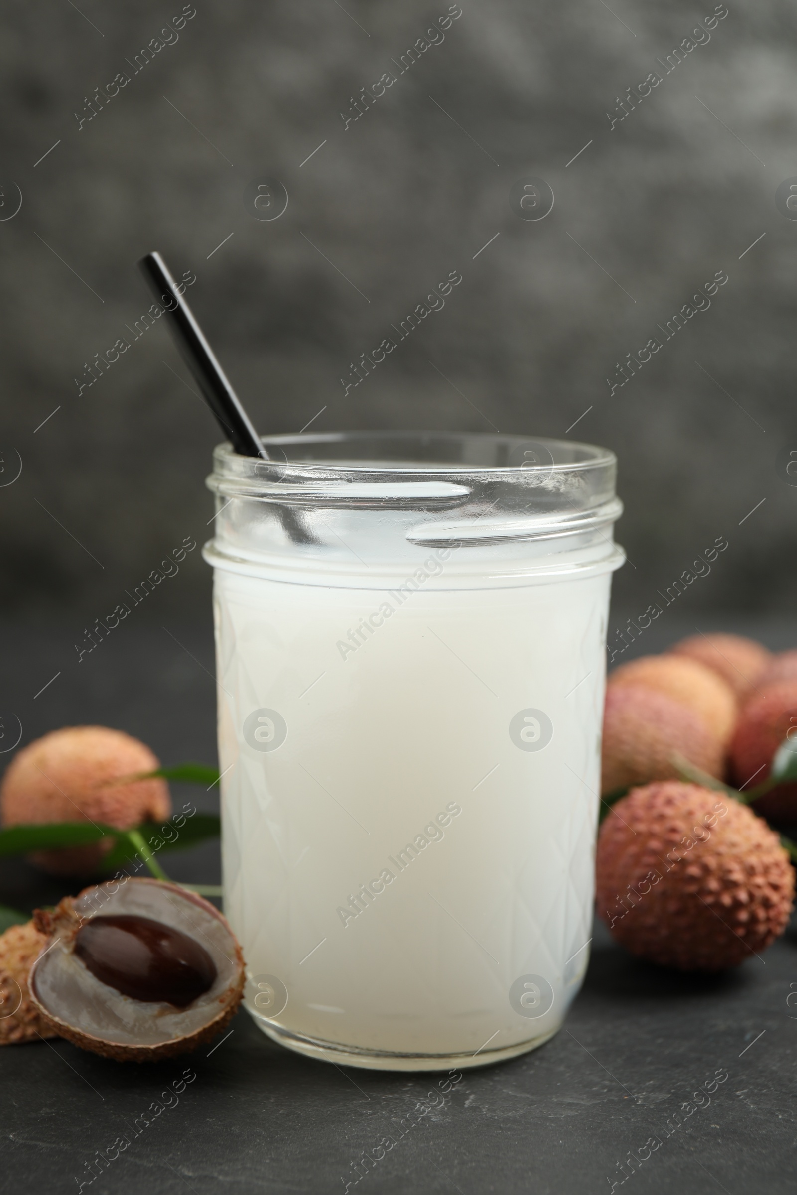 Photo of Fresh lychee juice and fruits on grey table